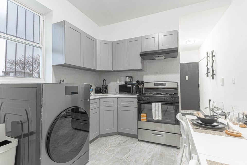 Modern kitchen with sleek appliances, dining set, and in-unit laundry