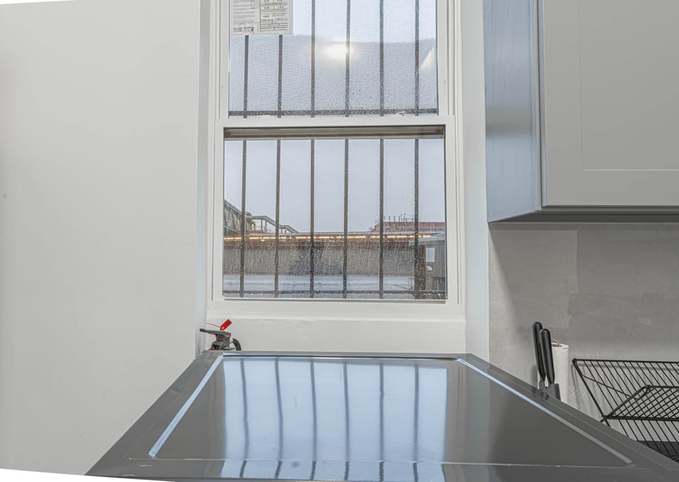 Kitchen window view with urban lights and sleek countertop setup including knives and dish rack
