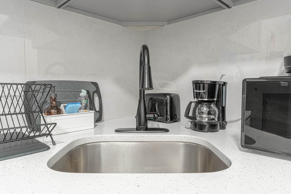 Well-stocked kitchen corner with sleek sink, coffee setup, and modern appliances