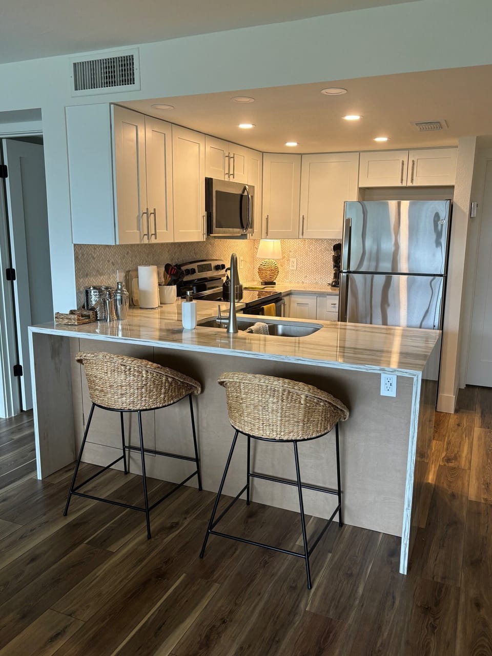 Cook your favorite meals in this modern kitchen featuring stainless steel appliances, elegant white cabinetry, and a convenient breakfast bar for casual dining.