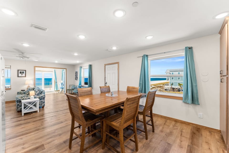 Gather around this beautiful dining table while ocean views and turquoise curtains create your perfect coastal retreat atmosphere.