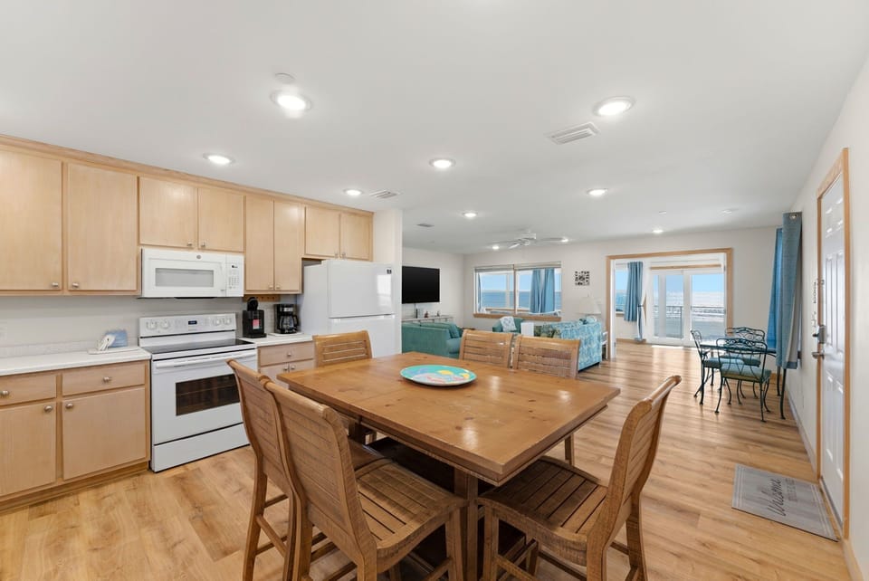 Gather around the wood dining table after a day at the beach, then step out to the balcony where ocean views stretch endlessly before you.