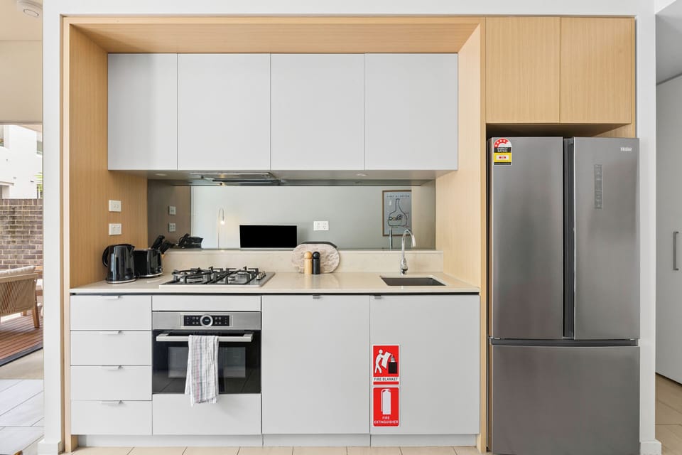 The sleek kitchen combines warm timber finishes with modern appliances, offering everything you need to prepare light meals or enjoy a relaxed dinner at home.