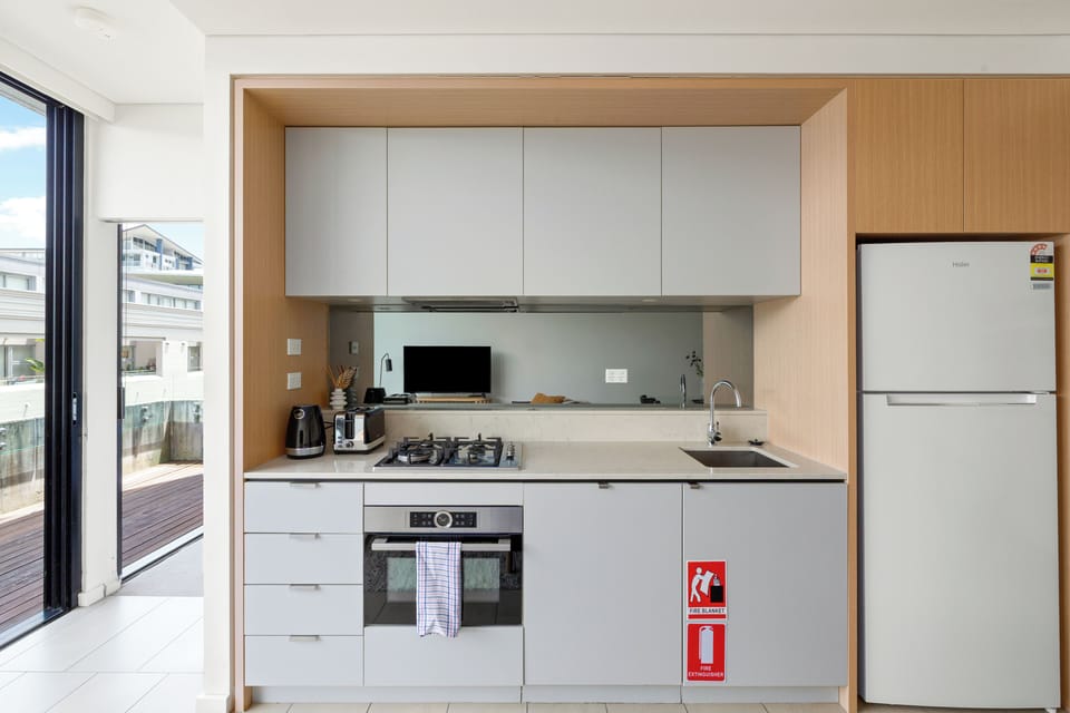 The sleek kitchen combines warm timber finishes with modern appliances, offering everything you need to prepare light meals or enjoy a relaxed dinner at home.