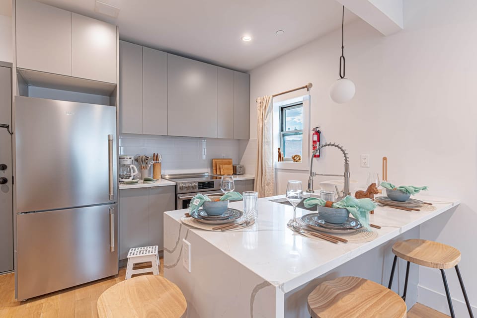 Kitchen nook with dining bar and modern appliances in bright Scandinavian Bushwick 1BD