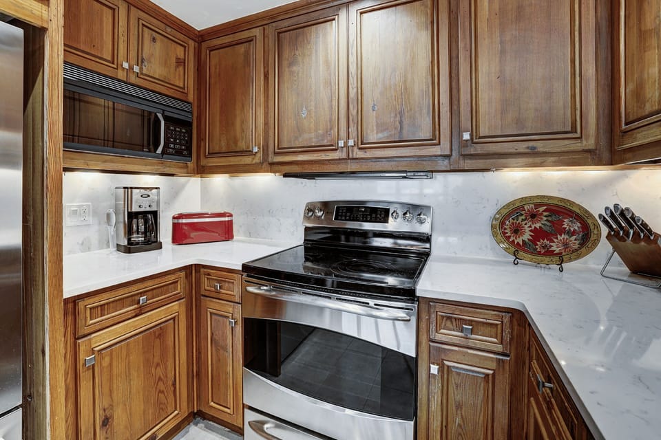 Fully equipped kitchen with rich wood cabinetry and granite countertops — ideal for preparing hearty post-ski dinners or cozy breakfasts in.