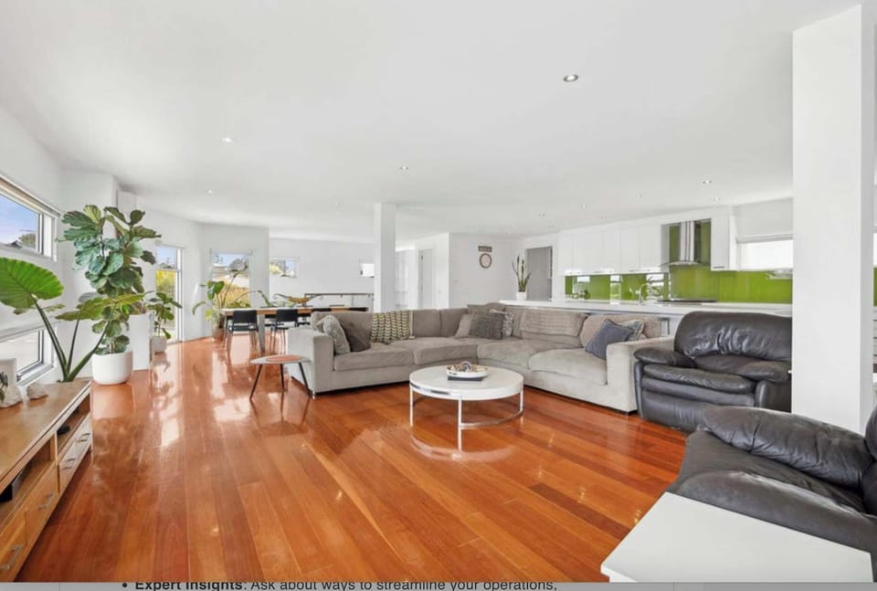 The upstairs living area features an open-concept design that seamlessly connects the living, dining, and kitchen spaces with polished timber floor. 