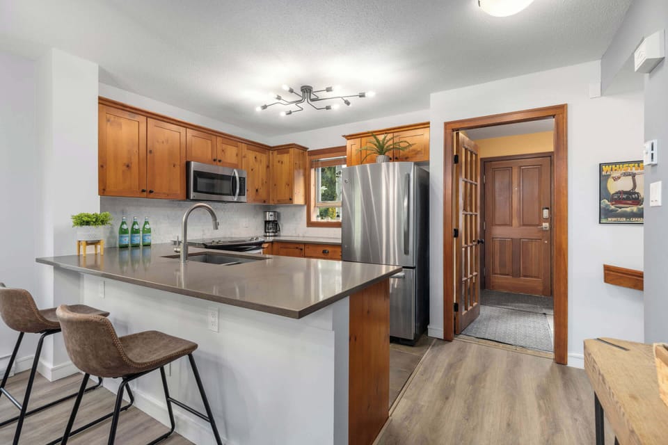 - Stainless fridge and smooth stone counters in a bright kitchen  
- Bar seating perfect for quick breakfasts or evening chats  
- Easy access to the entry and living room  
