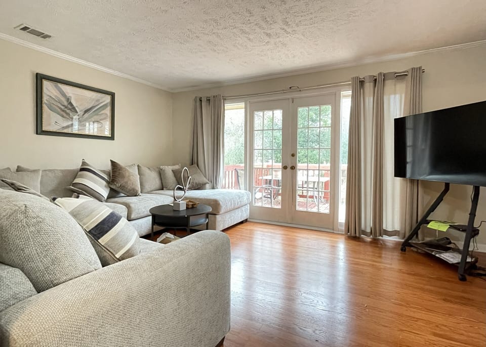 Floor to ceiling windows and doors looking out on deck and backyard.