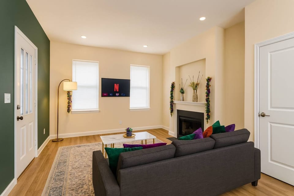 Bright living room with wall-mounted smart TV, deep green accent wall, and cozy fireplace nook.