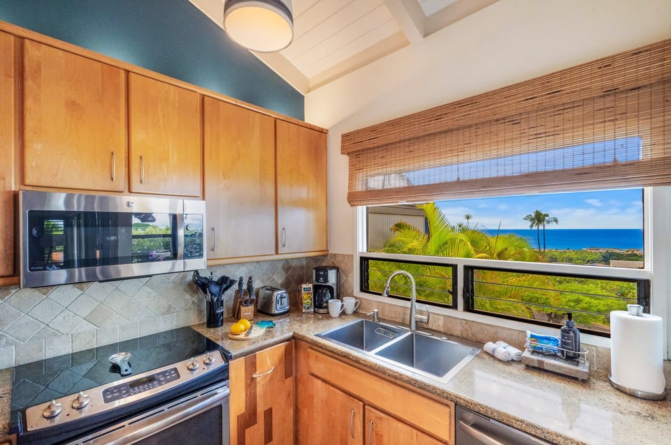 Stoves and counters line the walls, greenery and waves glowing through the windows.