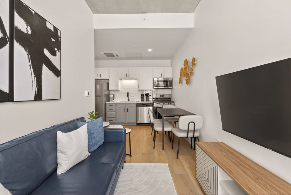 Relax or work with ease—smart TV, modern leather sofa, and dining area in a bright open-concept space.