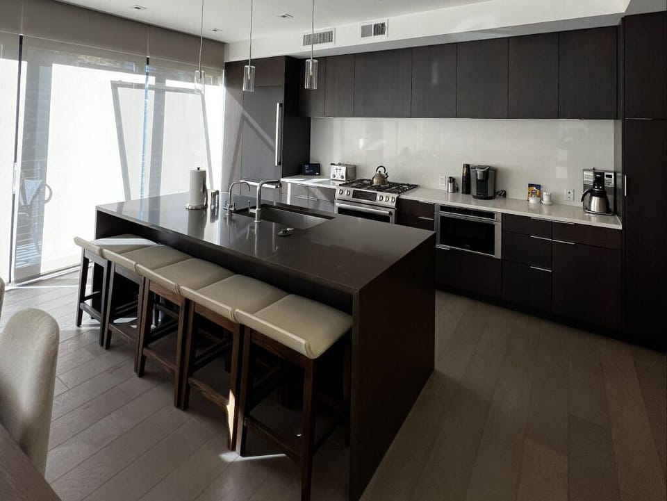 The contemporary kitchen is equipped with sleek dark cabinetry, high-end appliances, and a large island with seating for casual dining.