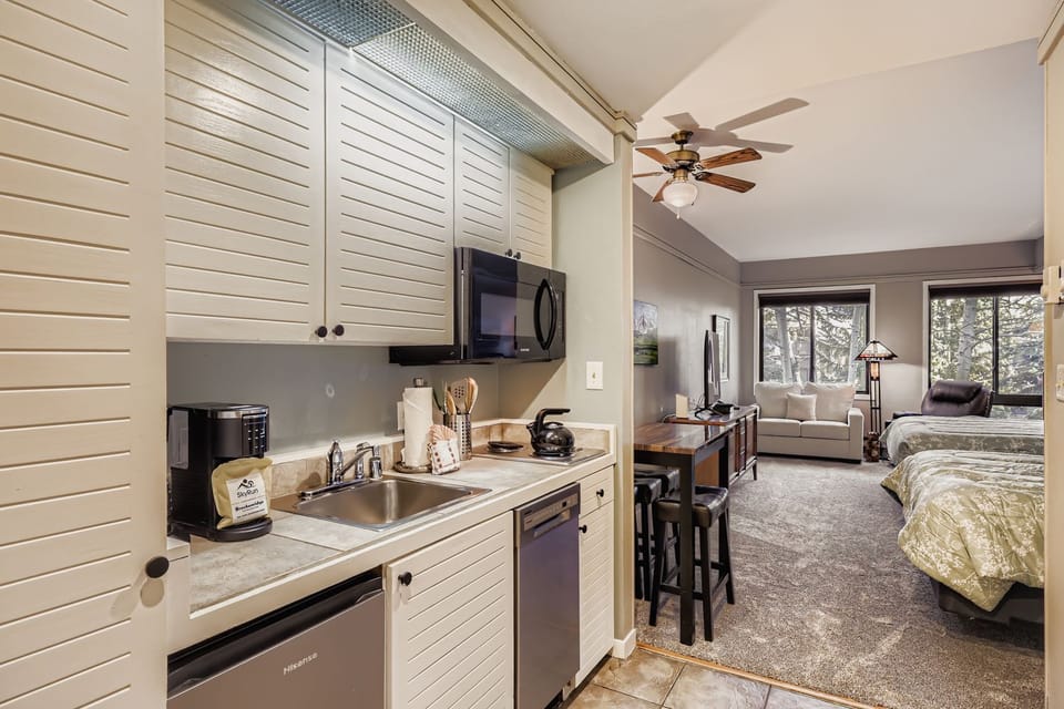 Your cozy studio perfectly blends comfort and convenience with a fully equipped kitchenette, comfortable seating area, and peaceful sleeping space overlooking nature's beauty through large windows.
