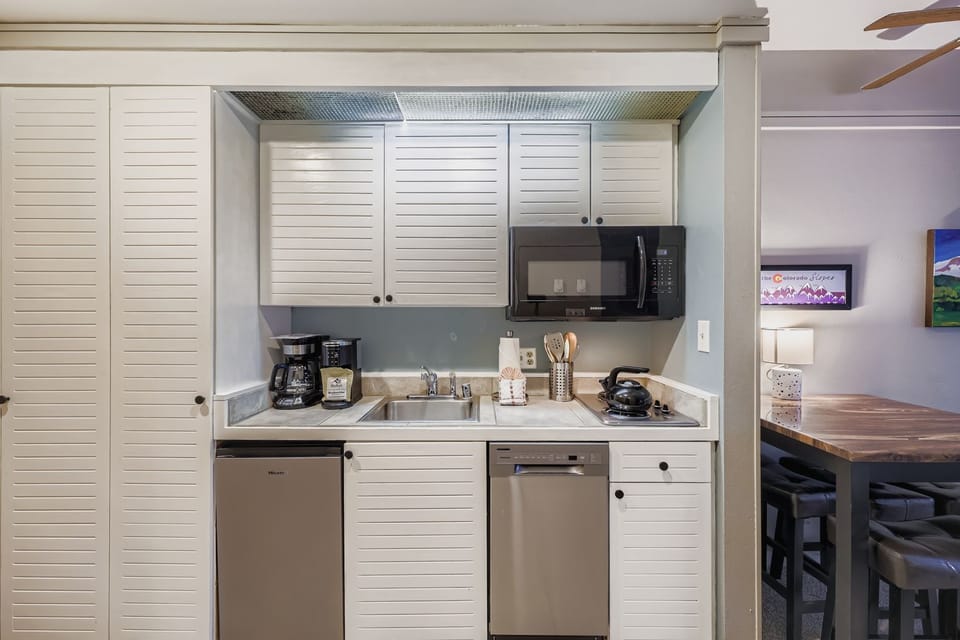 Step into your fully-equipped kitchenette where morning coffee and home-cooked meals await. Clean white cabinetry, stainless steel appliances, and thoughtful touches create the perfect space for your culinary adventures.