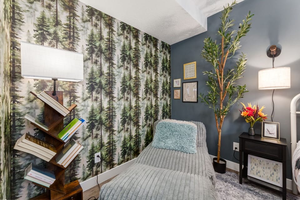 Potted plants, curated wall art, and a warm floor lamp add depth and dimension throughout the room. The greenery softens the bold patterns while maintaining a fresh, styled look in every corner.