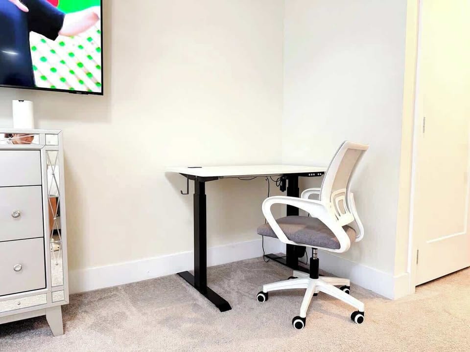 The upstairs master bedroom features a dedicated and comfortable workspace, complete with a height-adjustable desk and an ergonomic office chair.
