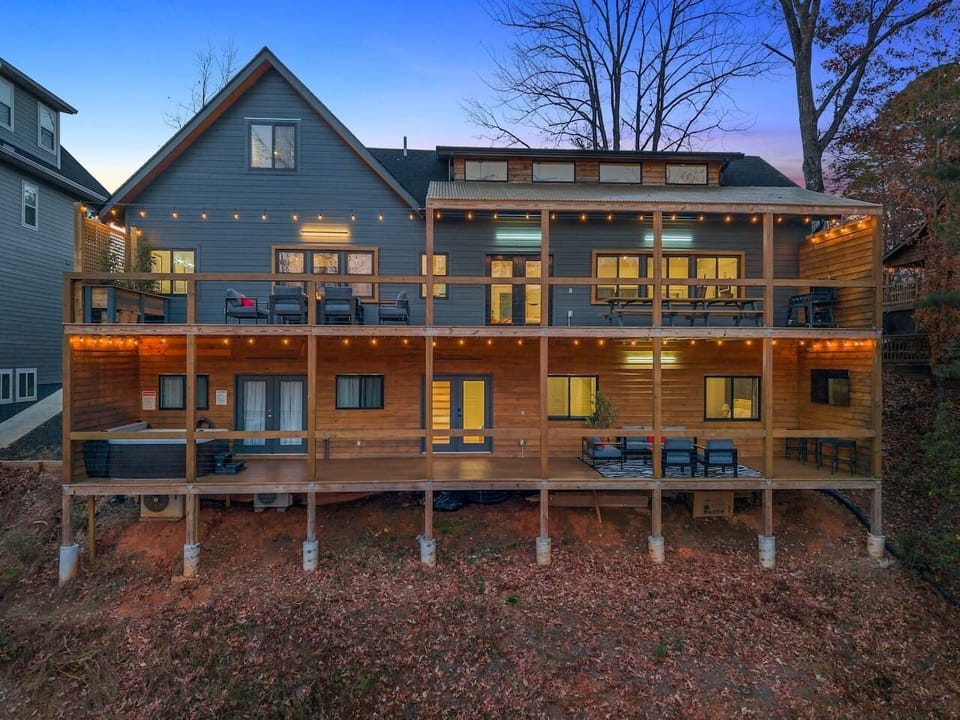Two-level decks at twilight with a propane fire pit, outdoor TV, and hot tub—perfect for cozy evenings under the lights