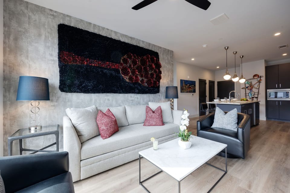 Unit 1: Modern open concept living area with floor to ceiling windows, designer furniture, smart TV, and access to private patio.