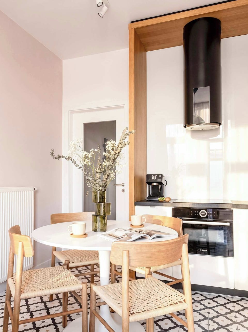 Cozy dining area set next to the modern kitchen, featuring a round table and natural wooden chairs.