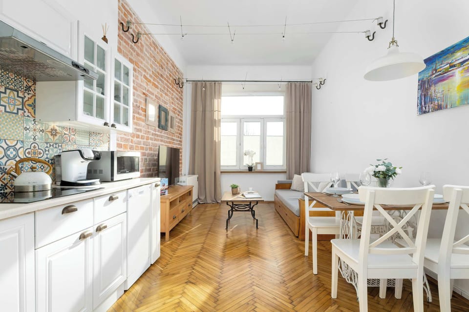 A spacious kitchen and dining area with a large window allowing natural light. The dining table is set for meals in a cozy, homey atmosphere.