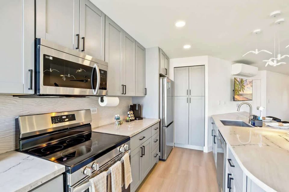 Prepare your favorite meals in this fully-equipped and renovated, contemporary kitchen, boasting sleek gray cabinetry, stainless steel appliances, and ample marble-style countertop space.