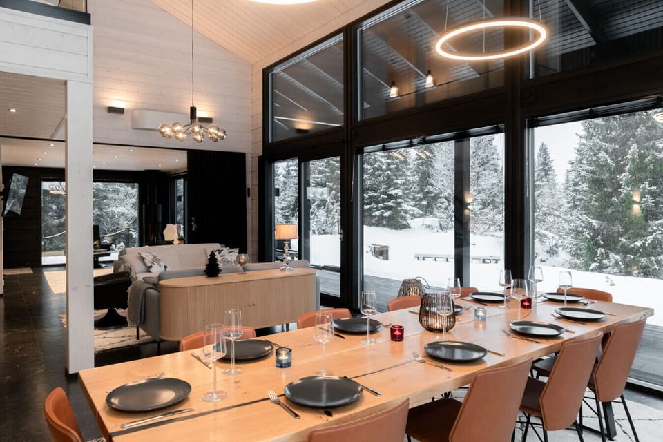 The spacious living room features full-height windows, a high ceiling, and comfortable seating, creating a bright and relaxing atmosphere.