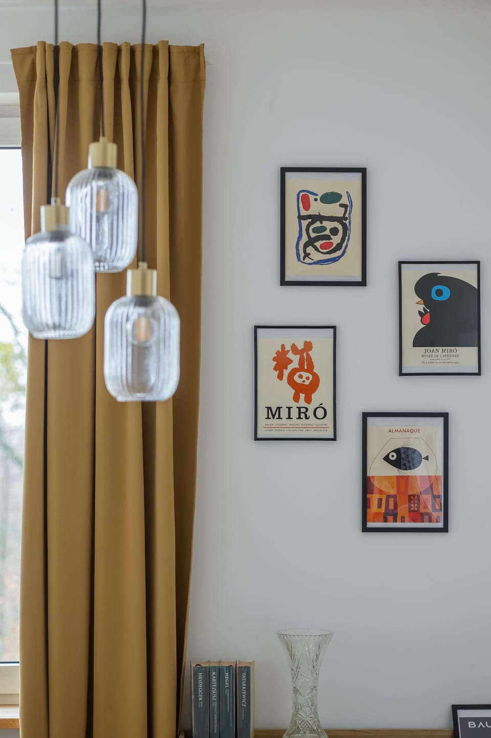 Elegant hanging lights positioned near framed posters and mustard curtains, creating a warm ambiance.