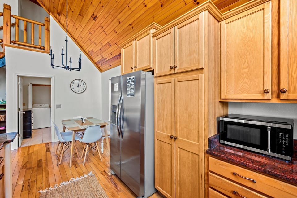 Warm wood cabinets and stainless steel fridge in the full kitchen.