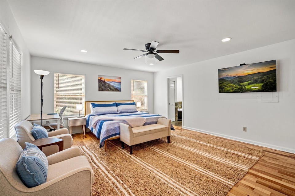Bright  king bedroom with light walls and a ceiling fan for comfort.