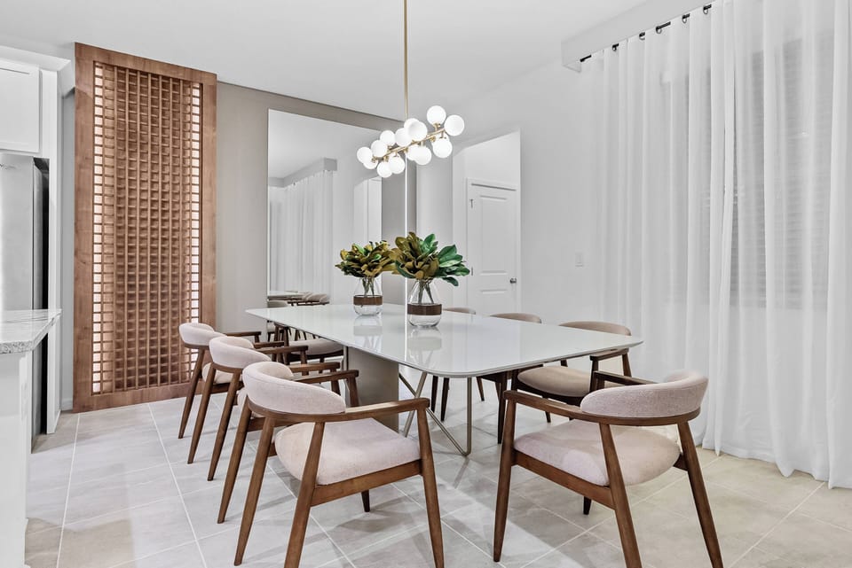 Join us at the elegant marble dining table, bathed in soft natural light from sheer curtains. The warm wooden chairs create a charming atmosphere, ensuring every meal is a delightful experience in this beautifully designed space.