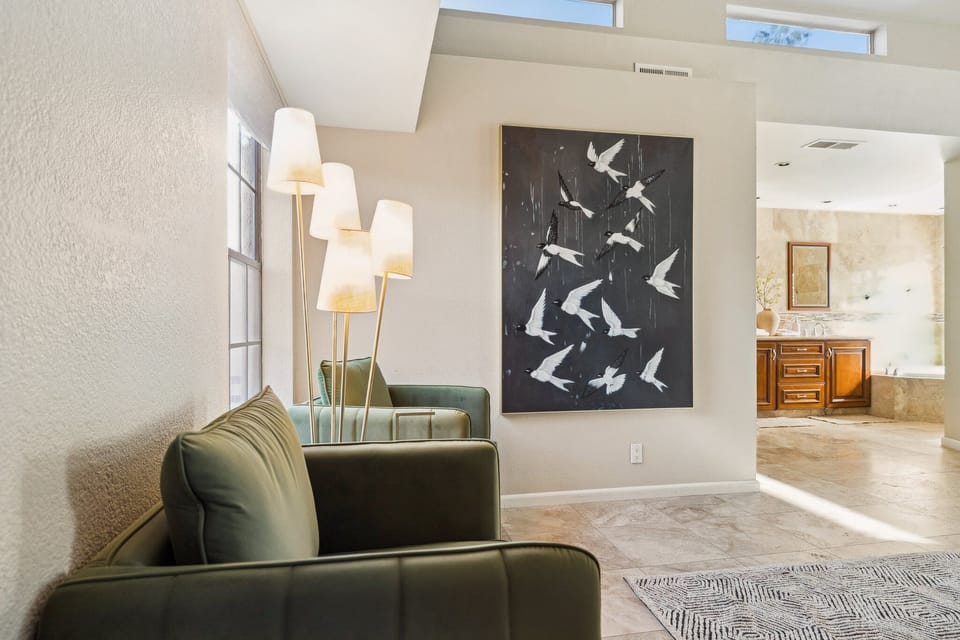 Bright sitting area with modern art and cozy green armchairs