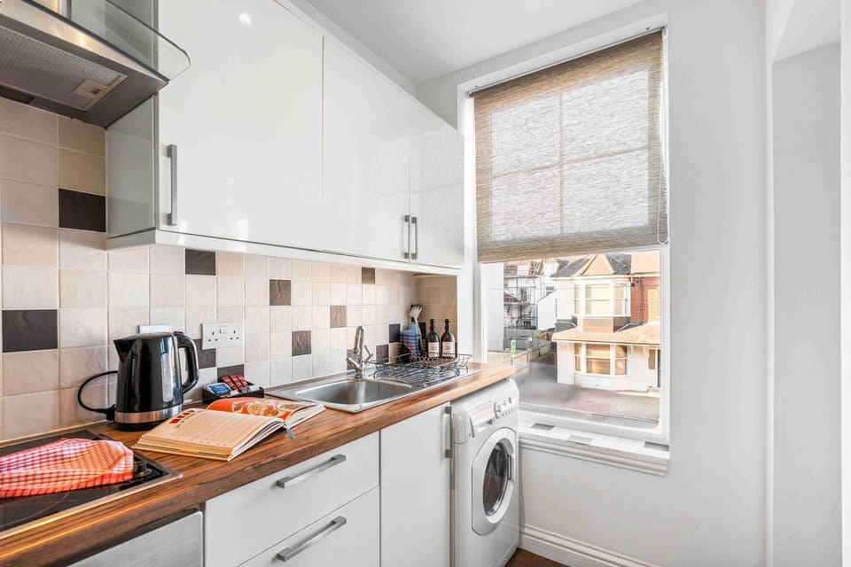 Modern fully equipped kitchen with stainless steel appliances and a sea-view visible through a distant window