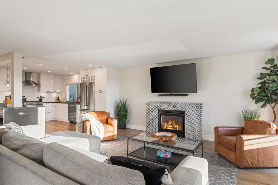 Bright open living room with fireplace, TV, and sofa.