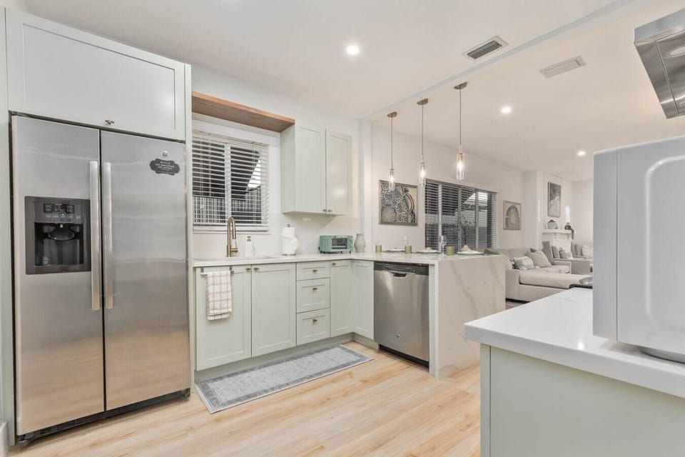 Kitchen with stainless steel refrigerator, dishwasher, white cabinets and island