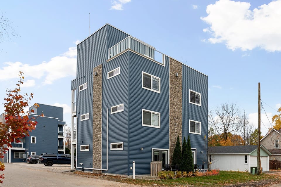 This contemporary residence features blue siding, stone panels, and a rooftop terrace — offering stylish comfort in a quiet, tree-lined neighborhood.