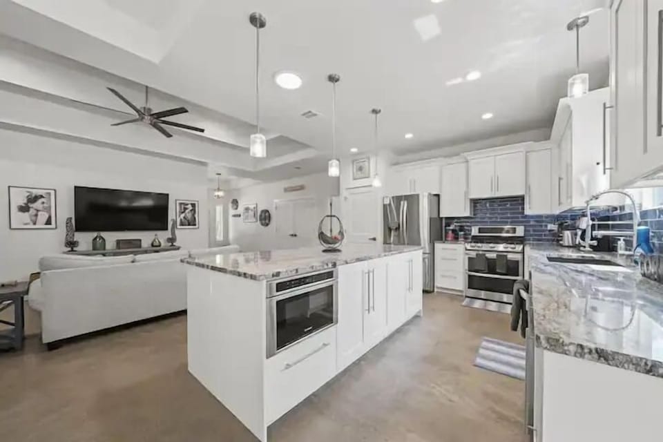 A bright, modern kitchen with a large island, stainless steel appliances, and sleek white cabinetry.