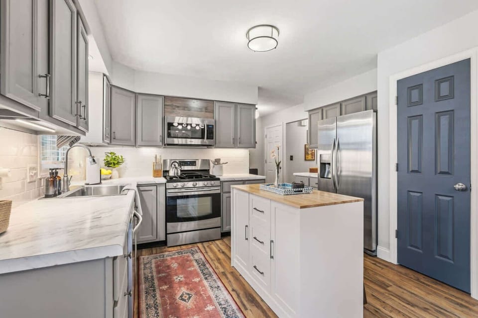 Bright kitchen w/ stainless range, white cabinetry & colorful runner rug.