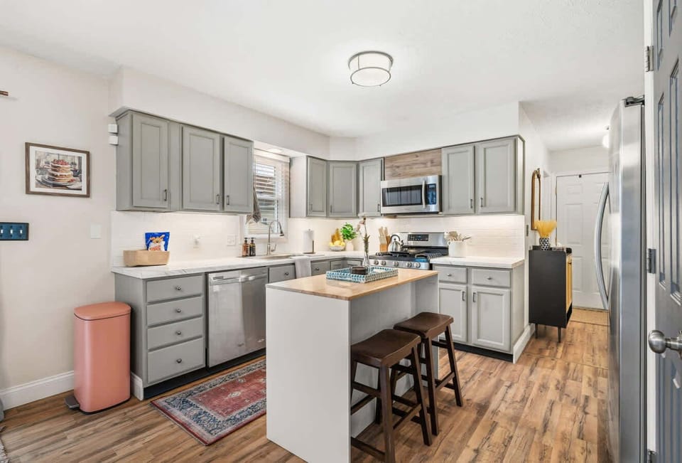 Clean, modern kitchen w/ stainless appliances, white cabinets & island seating.