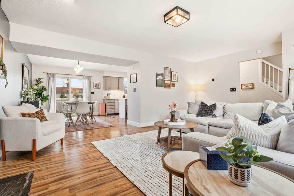Open living room filled w/ light, featuring comfy seating & wood floors.
