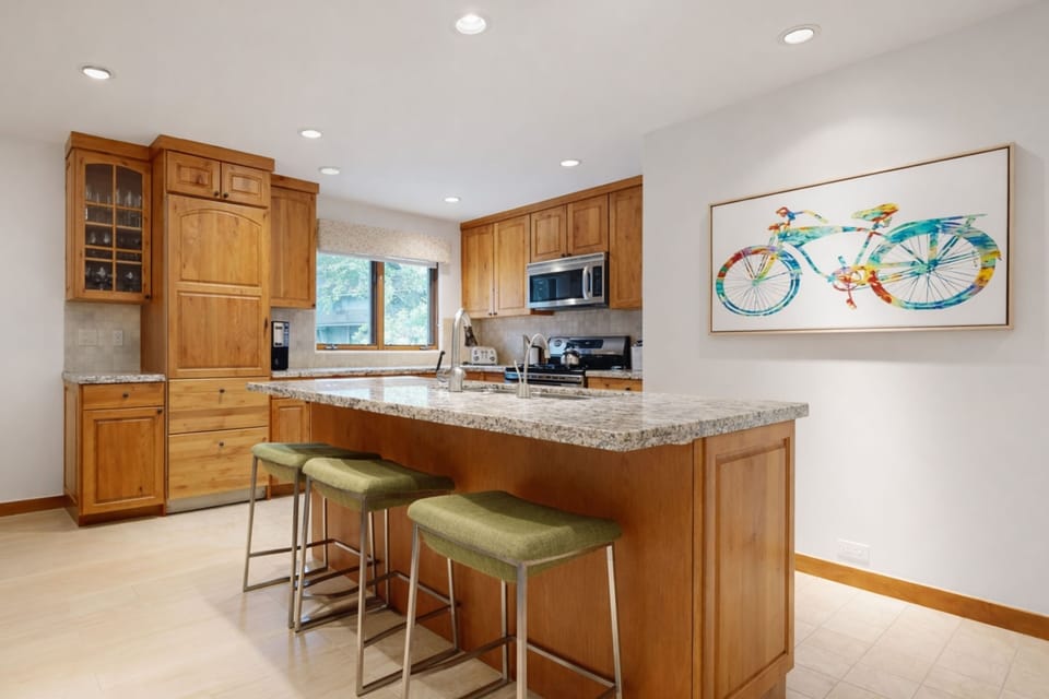 Your fully equipped kitchen features warm wood cabinets, granite counters, and a breakfast bar perfect for morning coffee or casual dining together.