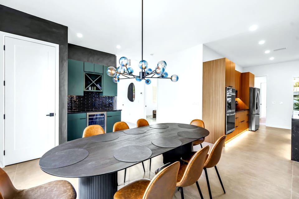 Designer dining space with statement lighting, bar nook, and sleek modern kitchen