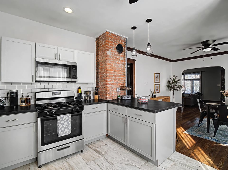 Stylish kitchen w/ white cabinets, stainless appliances & breakfast bar