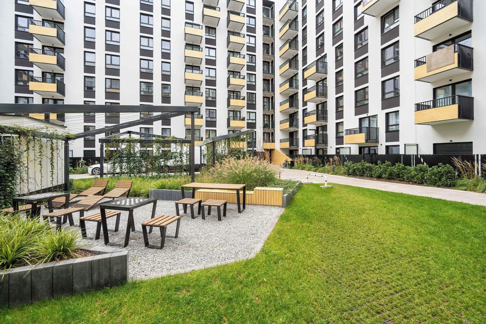Exterior courtyard of a modern apartment complex with green landscaping and seating areas.