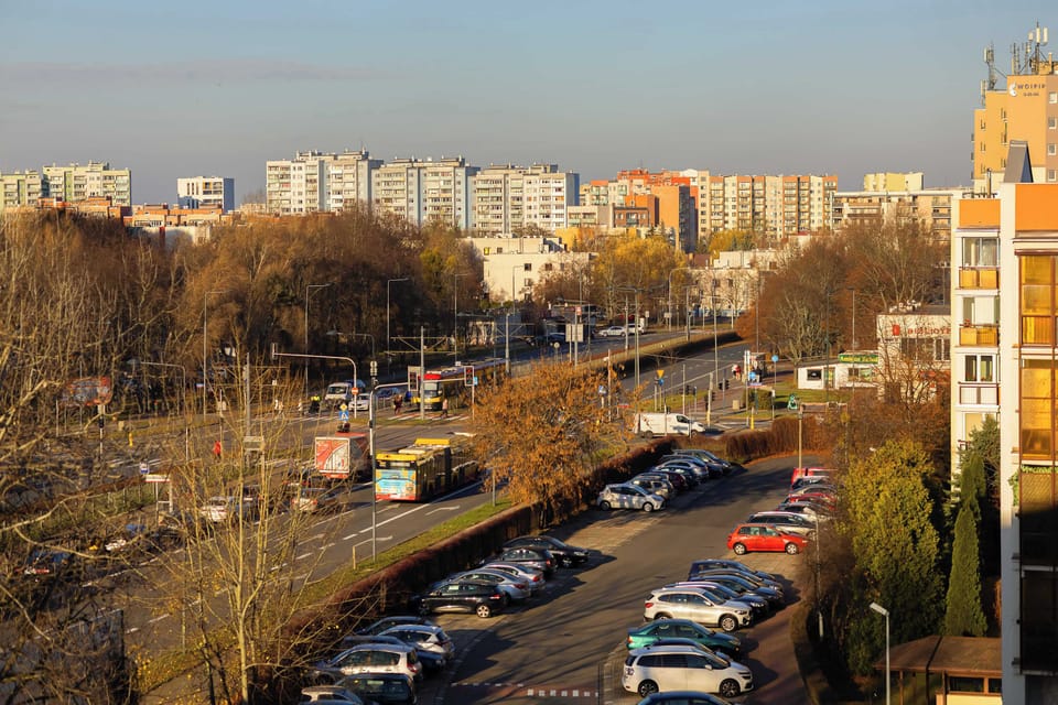 A busy urban street captured at sunset. Cars line the road while warm light reflects off surrounding buildings.