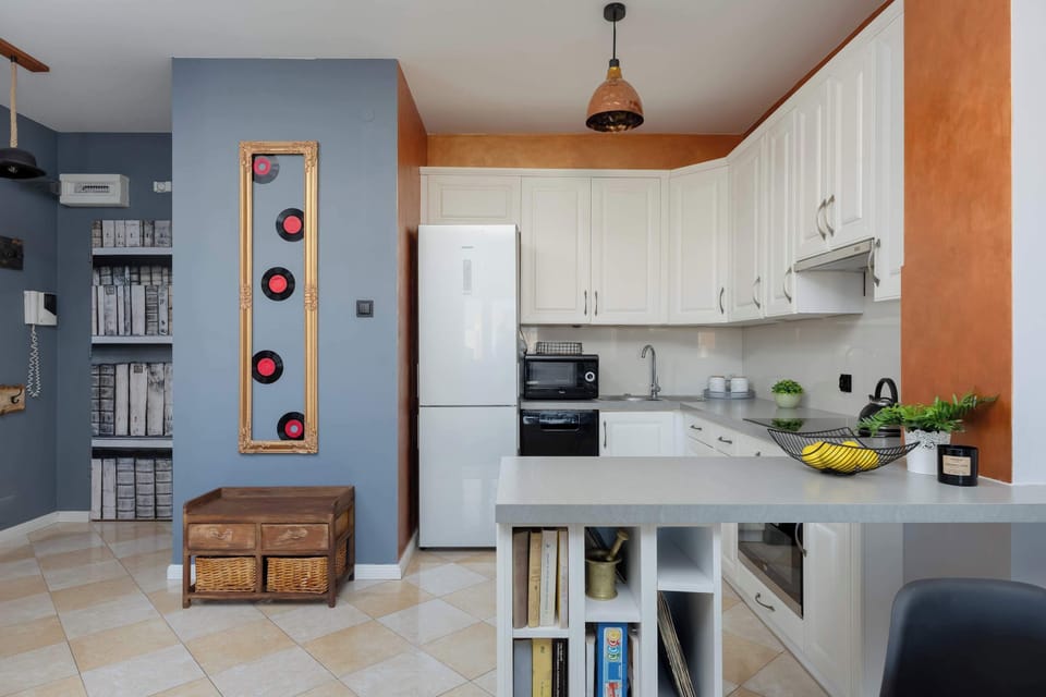A modern kitchen with white cabinetry and stainless-steel appliances. Decorative elements and plants add warmth to the space.