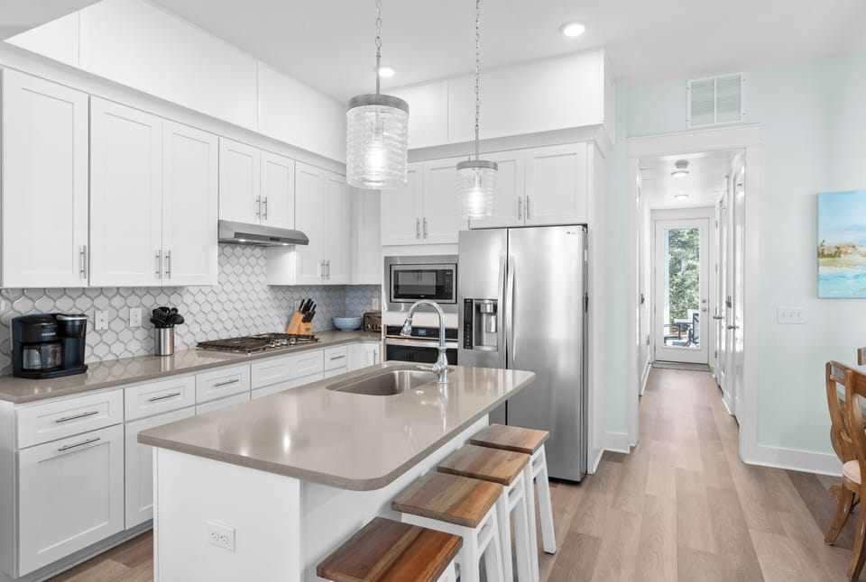 Modern kitchen with a large island, bar seating, stainless steel appliances, and pendant lights.