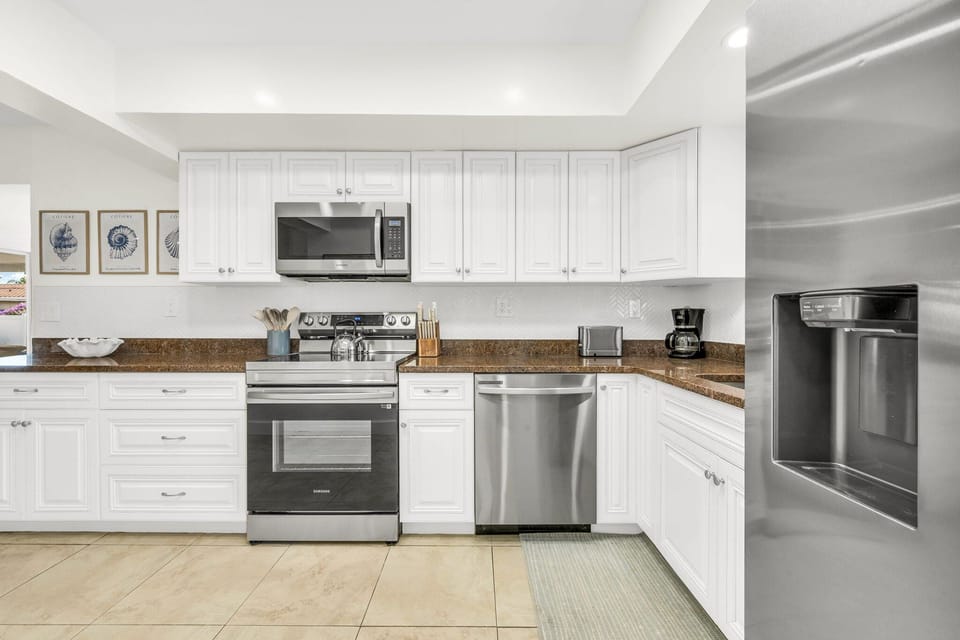 A spacious, light-filled kitchen offering stainless steel appliances, rich countertops, extensive cabinetry, and thoughtful amenities such as a coffee maker, blender, and toaster for effortless cooking and entertaining.