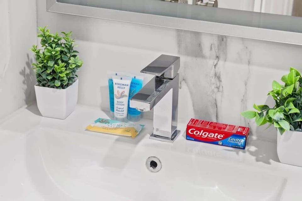 A close-up of the sink showing complimentary toiletries like toothpaste, toothbrush kit, and hand cream. Guests have everything they need for a comfortable stay.