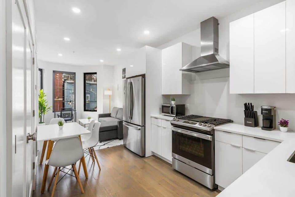 A bright, modern kitchen with glossy white cabinets, stainless steel appliances, and a clean open layout that flows smoothly into the living and dining areas. Perfect for cooking while staying connected with the rest of the space.
